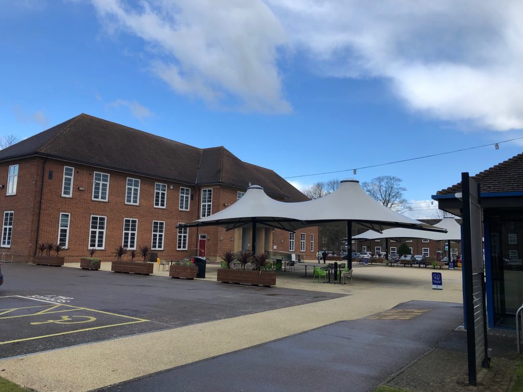 An original 1930s/1940s red bricked building at Cranfield with a covered seating area outside.