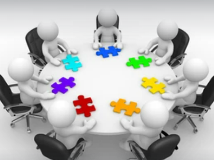 White humanoid figures sitting around a table with brightly coloured jigsaw puzzle pieces in front of them, indicating collaboration