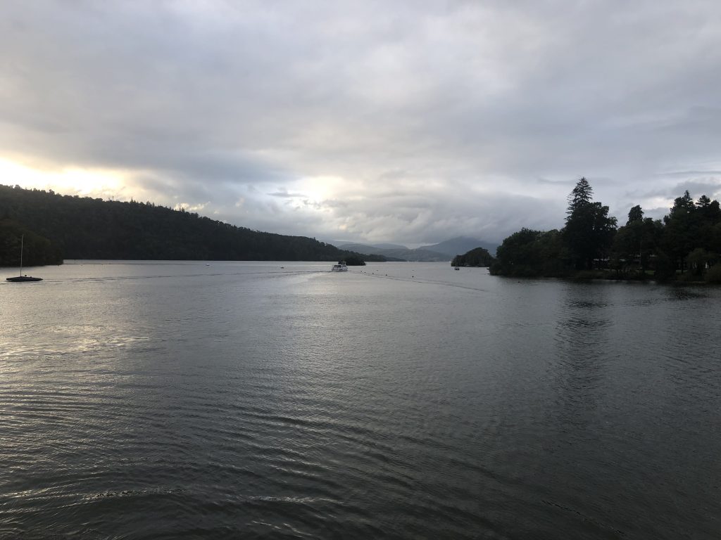 Evening shot of the lake taken from the boat. The lake is calm and the surrounding hills and trees can be seen in the fading light