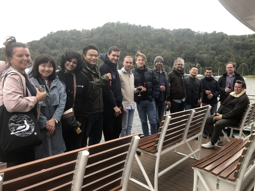 Group photo of 13 members of the TAS-S Node on the deck of the boat. Everyone looks a bit chilly but happy!