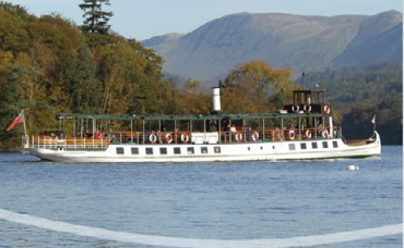 A photo of an old fashioned steamer on Lake Windermere. The Cumbrian hills can be seen in the background on this very sunny day.